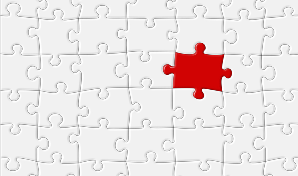 Red jigsaw puzzle piece fitting in to white jigsaw puzzle