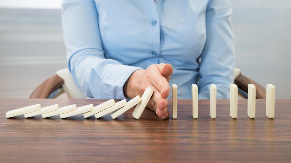 Woman stopping dominoes from falling