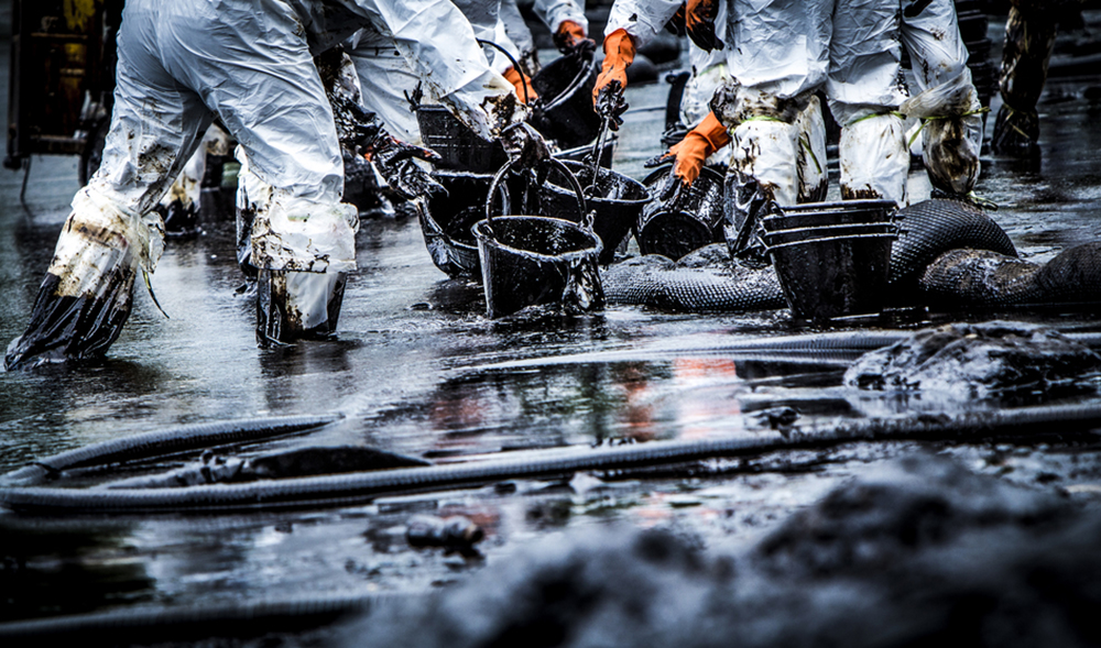 An oil spill being cleaned by individuals with buckets